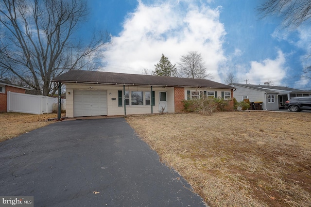 ranch-style home featuring driveway, an attached garage, and fence