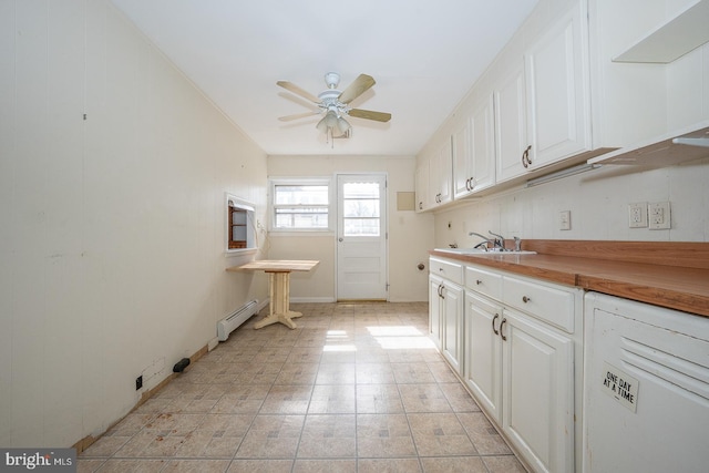 kitchen with ceiling fan, a baseboard radiator, butcher block counters, a sink, and white cabinetry