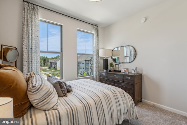 bedroom with baseboards and light colored carpet