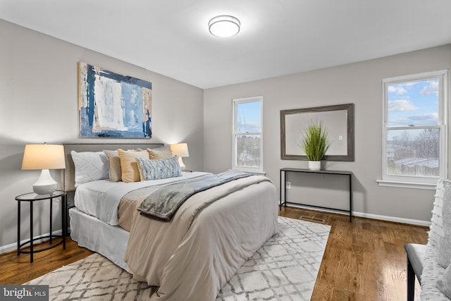 bedroom with wood finished floors, visible vents, and baseboards