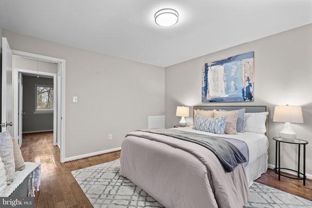 bedroom with wood finished floors, attic access, and baseboards