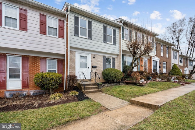 townhome / multi-family property featuring brick siding and a front yard