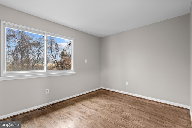 unfurnished room featuring visible vents, baseboards, and wood finished floors