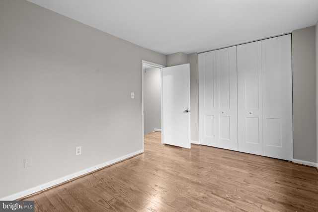 unfurnished bedroom with a closet, baseboards, and wood finished floors