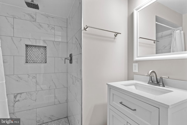 full bathroom with a tile shower and vanity