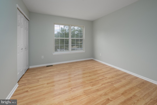 unfurnished bedroom with a closet, light wood-type flooring, visible vents, and baseboards