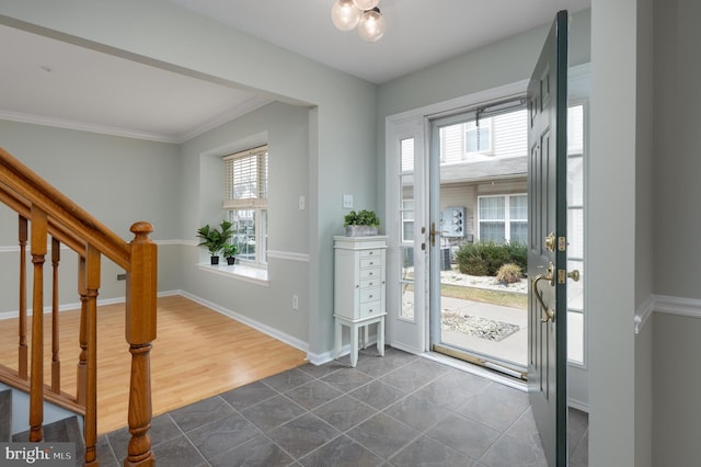 foyer entrance featuring dark tile patterned flooring, plenty of natural light, baseboards, and stairs