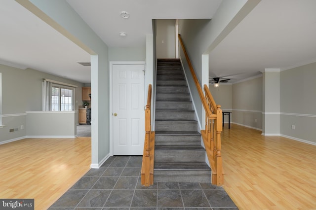 stairs featuring crown molding, ceiling fan, baseboards, and wood finished floors