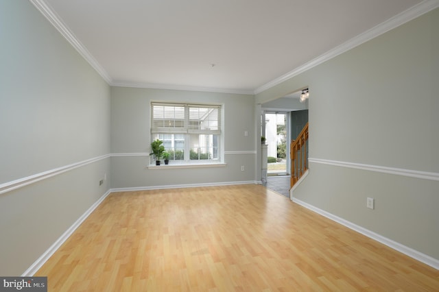 unfurnished room with stairway, ornamental molding, light wood-style flooring, and baseboards