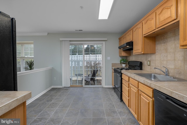 kitchen with under cabinet range hood, a sink, a healthy amount of sunlight, decorative backsplash, and black appliances