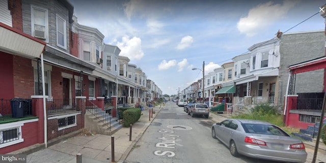 view of street with a residential view, curbs, street lights, and sidewalks