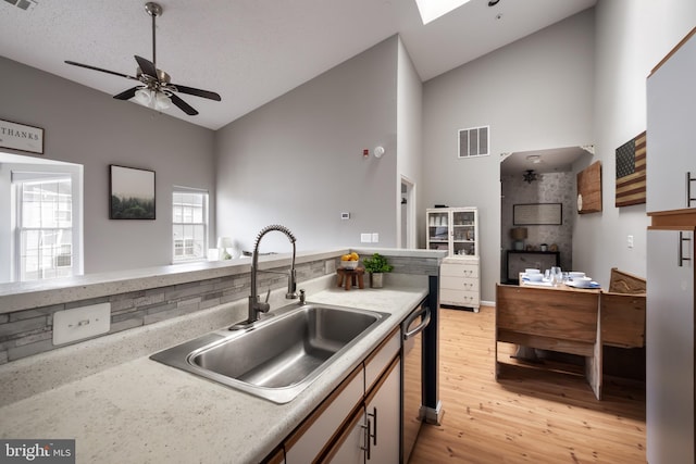 665 Constellation Sq SE Unit F, Leesburg, VA 20175 - kitchen with a sink, light wood finished floors, high vaulted ceiling, a ceiling fan, and stainless steel dishwasher