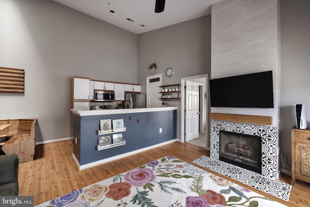 665 Constellation Sq SE Unit F, Leesburg, VA 20175 - kitchen featuring appliances with stainless steel finishes, high vaulted ceiling, white cabinetry, a fireplace, and light wood-style flooring