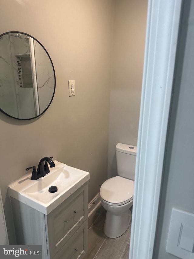 bathroom featuring toilet, baseboards, and vanity