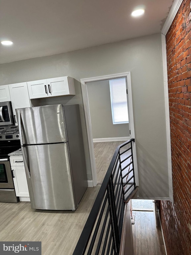 kitchen featuring stainless steel appliances, light wood-type flooring, and white cabinets