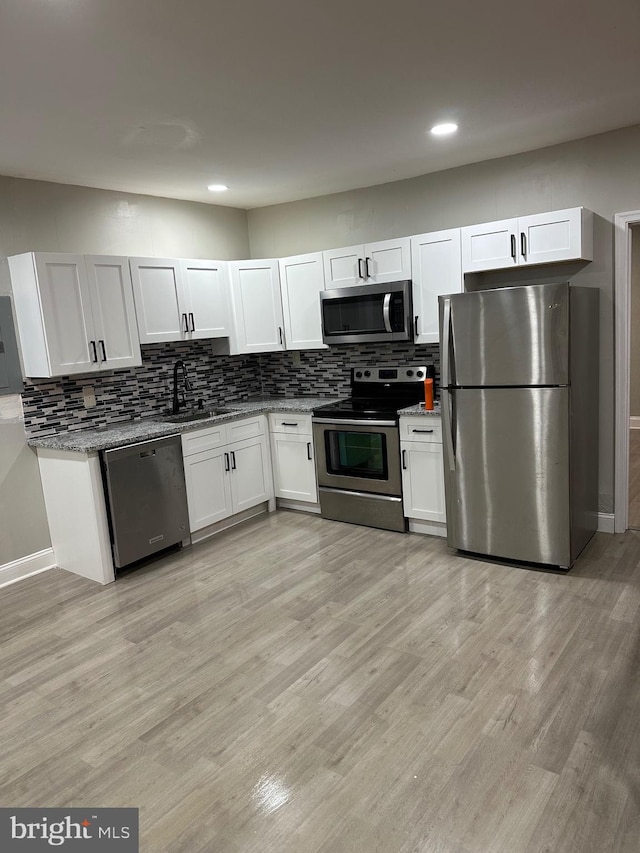 kitchen featuring light wood-type flooring, tasteful backsplash, stainless steel appliances, and a sink