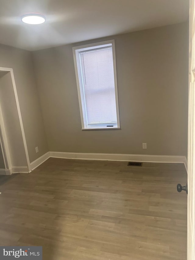 unfurnished room with wood finished floors, visible vents, and baseboards