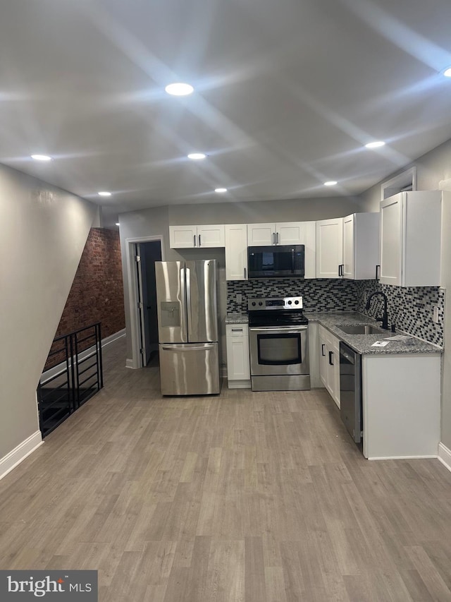 kitchen with white cabinets, light wood finished floors, stainless steel appliances, and a sink