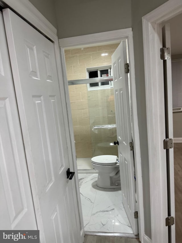 bathroom with marble finish floor and toilet