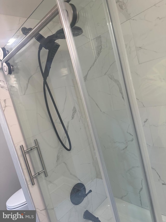 full bathroom with toilet and a marble finish shower