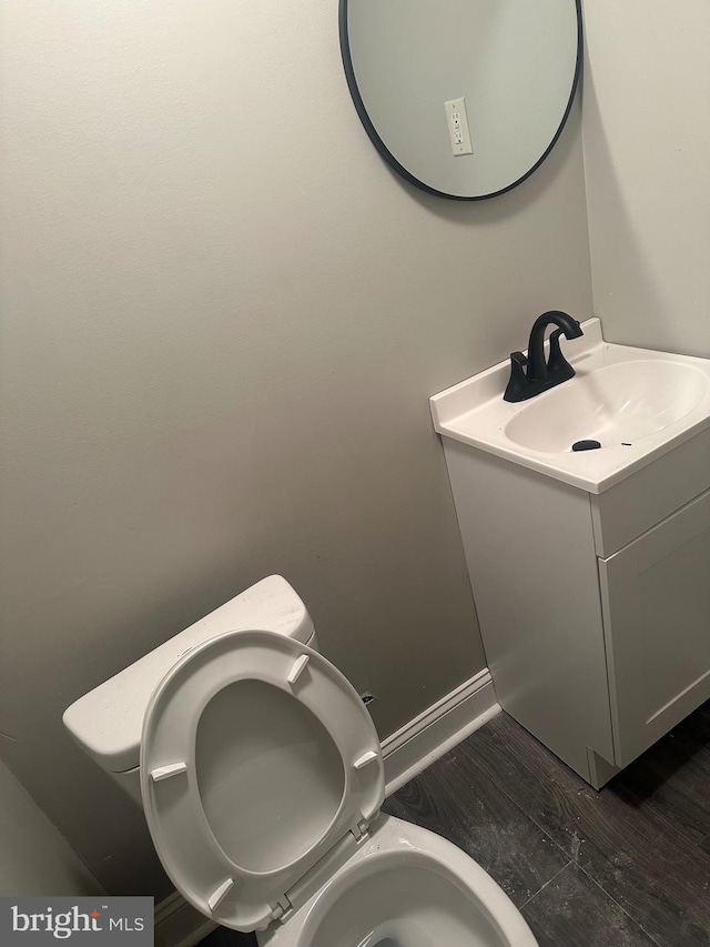 bathroom featuring baseboards, vanity, toilet, and wood finished floors