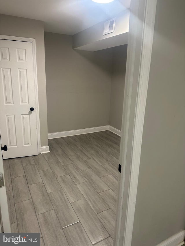 finished below grade area featuring wood tiled floor, visible vents, and baseboards