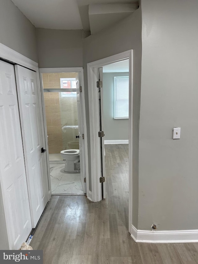 hall featuring baseboards and wood finished floors