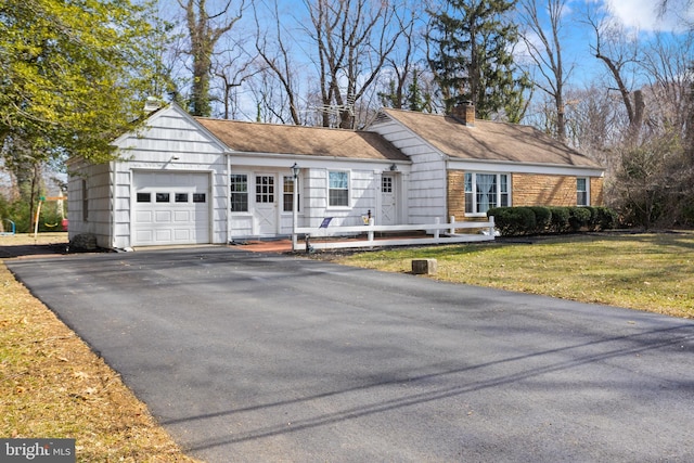 ranch-style house with aphalt driveway, a chimney, an attached garage, and a front yard