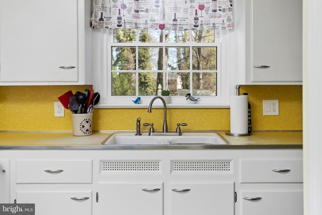 kitchen with light countertops, a sink, and white cabinetry