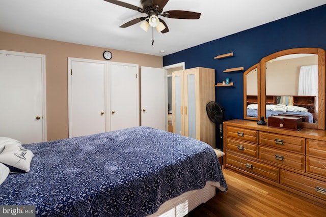 bedroom featuring ceiling fan, two closets, and wood finished floors