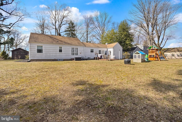 rear view of house with fence, a lawn, and a playground