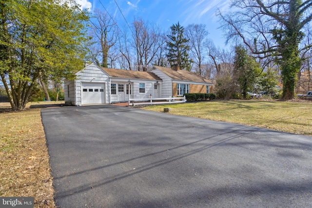 single story home with an attached garage, aphalt driveway, and a front yard