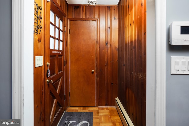 entryway with a baseboard radiator and wooden walls