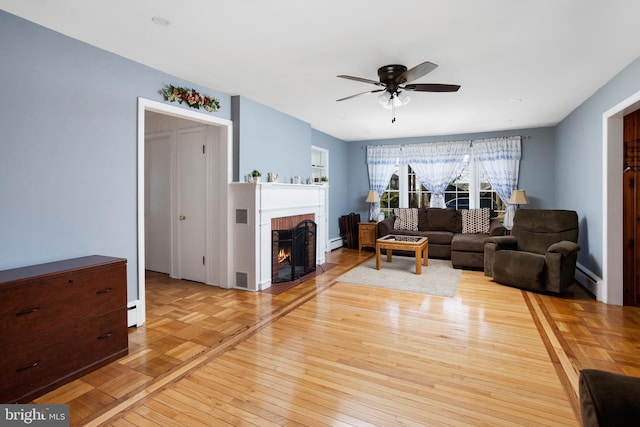 living area with parquet flooring, visible vents, a ceiling fan, a brick fireplace, and a baseboard heating unit