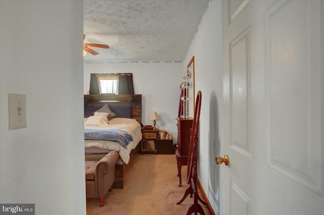 bedroom featuring light carpet, a textured ceiling, and a ceiling fan