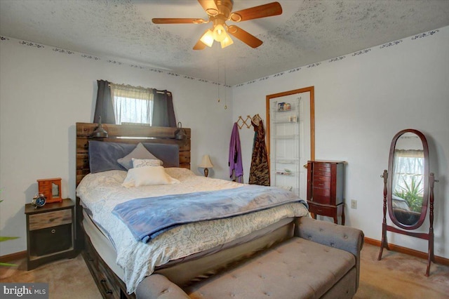 bedroom with light colored carpet, a textured ceiling, baseboards, and a ceiling fan