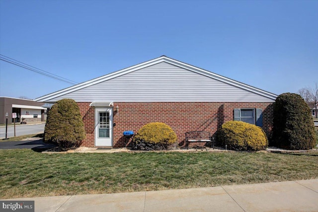 view of property exterior with brick siding and a lawn