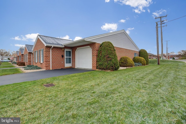 view of property exterior featuring brick siding, a yard, aphalt driveway, and a garage