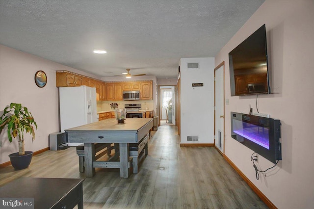 kitchen with light wood finished floors, visible vents, stainless steel appliances, and light countertops