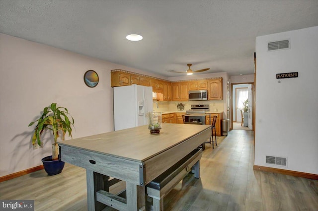 dining space with a ceiling fan, visible vents, light wood-type flooring, and baseboards