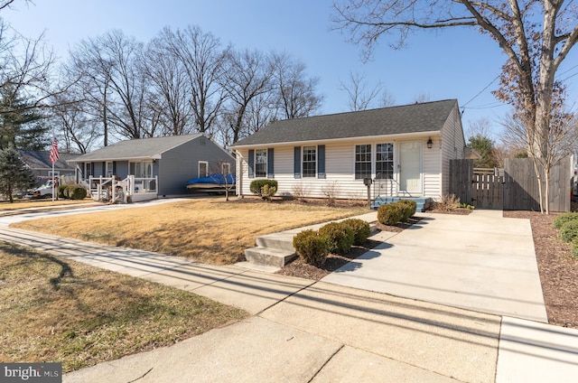 view of front of house featuring driveway, fence, and a front lawn