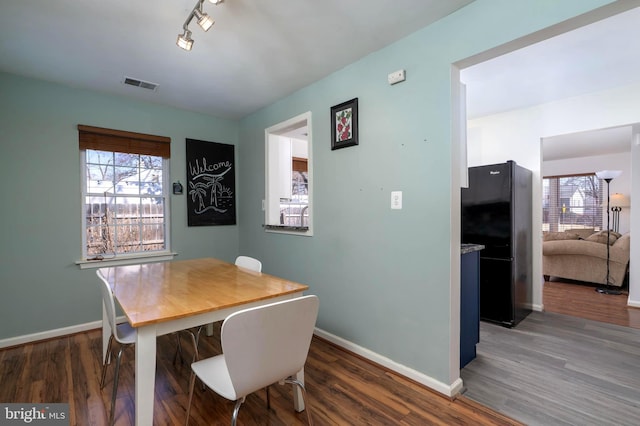 dining room featuring wood finished floors, visible vents, and baseboards