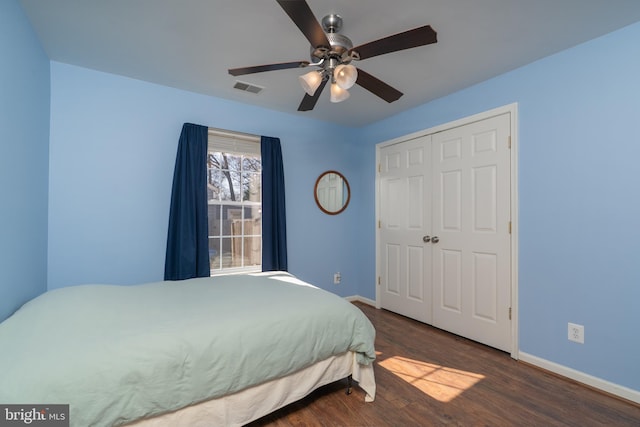 bedroom with baseboards, visible vents, a ceiling fan, dark wood finished floors, and a closet