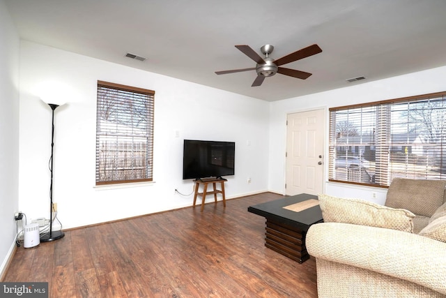 living room with a ceiling fan, visible vents, and wood finished floors