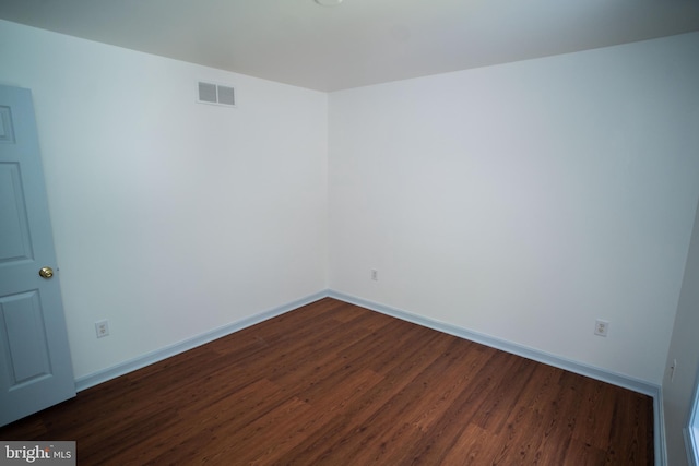 spare room featuring baseboards, visible vents, and dark wood-style flooring