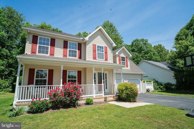 view of front of property with a garage, a porch, a front yard, and aphalt driveway