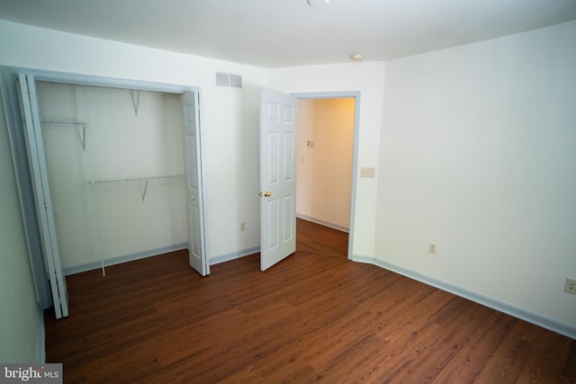 unfurnished bedroom featuring baseboards, a closet, visible vents, and wood finished floors