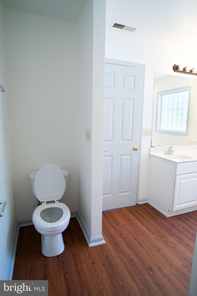 bathroom featuring visible vents, toilet, vanity, wood finished floors, and baseboards