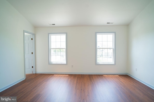 empty room with visible vents, dark wood finished floors, and baseboards