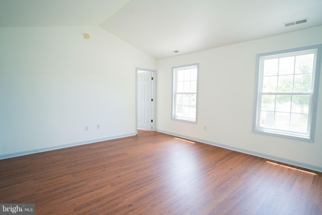 unfurnished room featuring vaulted ceiling, wood finished floors, visible vents, and baseboards